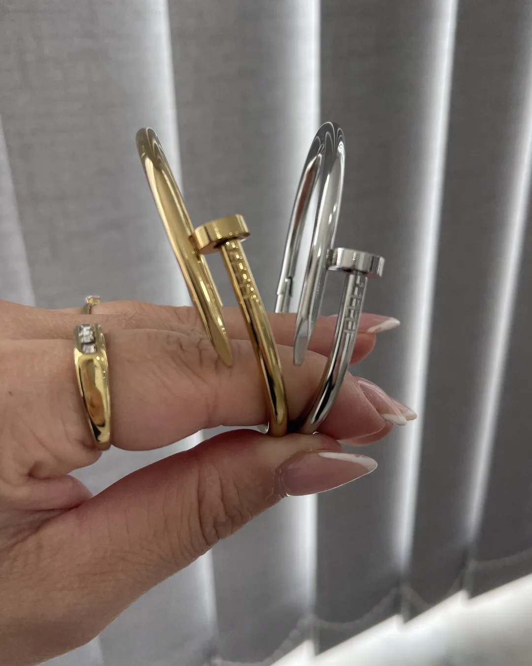 Bracelete Prego dourado e prata juntos na mão, foto real